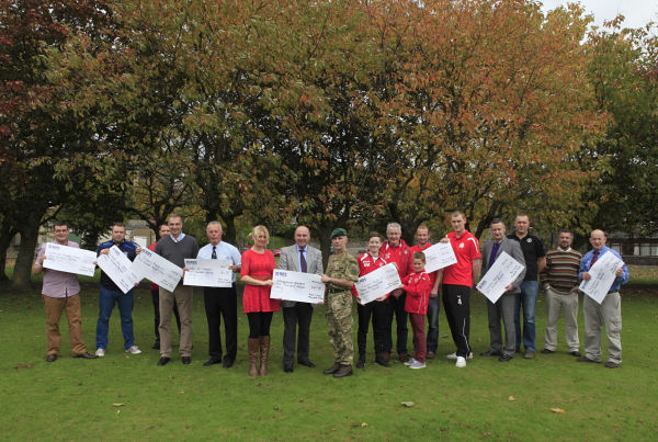 Recipients of funds with presentation cheques standing in park.